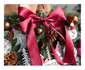 Detail of Christmas wreath with red bow, pine cones, and Santa Claus plush decoration