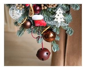 Macro detail of Christmas door wreath with red metal bells and embroidered stocking decoration