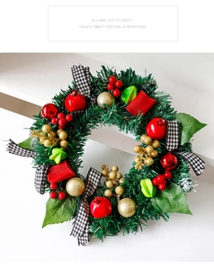 Détail d'une couronne de Noël avec baies rouges, boules dorées et nœud au motif pied-de-poule