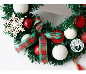 Détail d'une couronne de Noël avec nœud écossais, boules décorées et flocon en bois