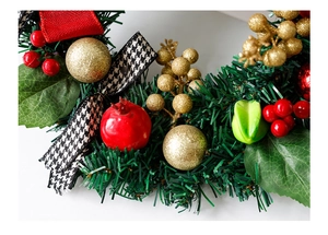 Vue détaillée de couronne de Noël avec baies rouges, boules dorées et nœud à motif pied-de-poule