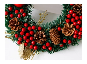 Détail d'une couronne de Noël avec aiguilles de pin vertes, baies rouges et feuilles dorées