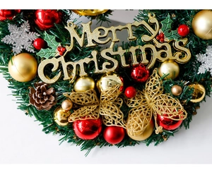 Détail d'une couronne de Noël verte avec lettrage doré Merry Christmas et boules