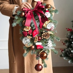 Christmas teardrop wreath with red bow, pine cones, and metal bell for door decor