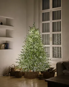 Close-up of a pre-lit Christmas tree with warm LED lights and a rustic rattan base