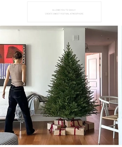 Green artificial Christmas tree with gift boxes in a modern living room setting