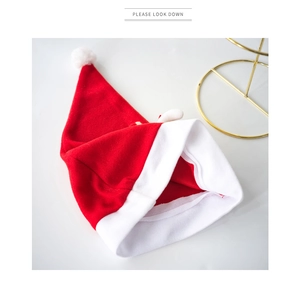 Detailed view of a red plush Christmas hat with a white pom-pom on a gold-framed stand