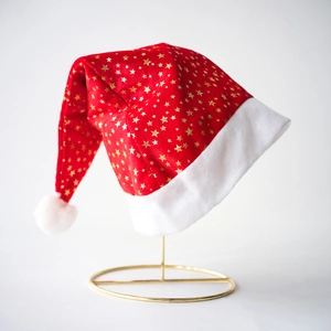 Festive red Christmas hat with gold stars and white plush trim on a metal display stand