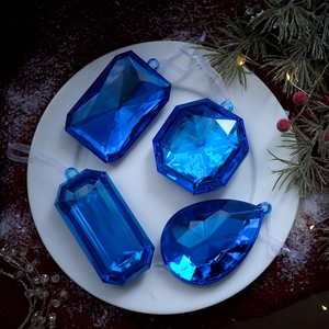 Adornos navideños de gemas azul estrellado con cintas sobre fondo festivo decorado