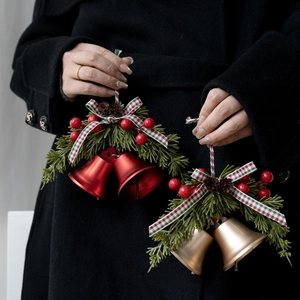 Christmas tree bell ornaments with red and gold metal finish and plaid bows held by model
