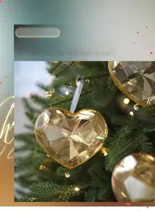 Macro shot of faceted champagne acrylic heart ornament hanging on a lush green Christmas tree