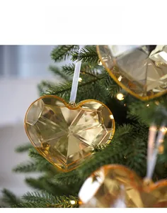 Detail of amber heart acrylic ornament with faceted cuts hanging on a Christmas tree