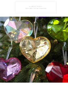 Close-up of faceted colorful acrylic heart ornaments hanging on a lighted Christmas tree