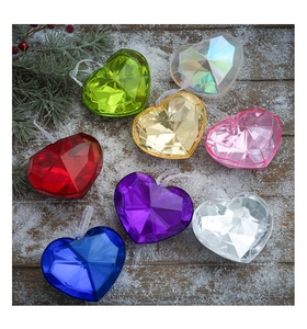 Close-up of colorful faceted acrylic heart ornaments on a festive snow-covered background