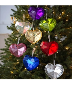 Macro shot of colorful faceted acrylic heart ornaments hanging on a Christmas tree
