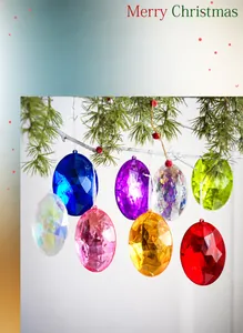 Gekleurde acryl eivormige hangers hangend aan een besneeuwde kerstboomtak met bessen