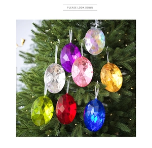 Primer plano de colgantes de huevo acrílicos de colores en un árbol de Navidad iluminado