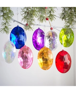 Set de ocho adornos coloridos en forma de huevo facetado colgados en rama de Navidad
