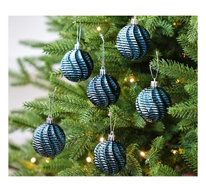 Gros plan de boules de Noël bleues à texture spirale avec cordons argentés sur sapin