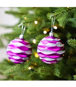 Close-up of purple glitter wave Christmas balls hanging on a pine tree branch