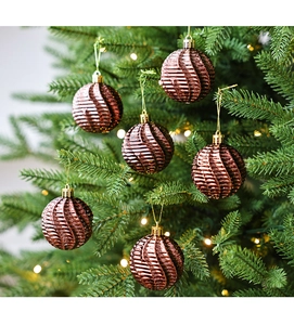 Détail de boules de Noël rouges à texture spirale avec attaches dorées sur sapin