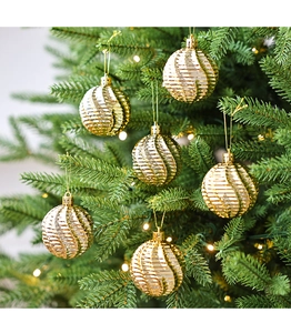 Détail de 6 boules de Noël dorées de 6cm avec rainures sur un sapin de fête