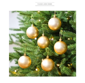 Primer plano de bolas de Navidad doradas con textura de copos en un árbol decorado