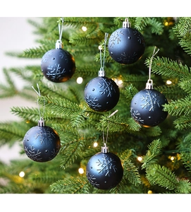 Bola de Navidad negra mate con relieve de copo de nieve colgada en un árbol decorado