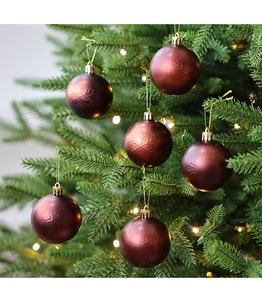 Primer plano de bolas de Navidad rojo oscuro con copos de nieve grabados en el árbol