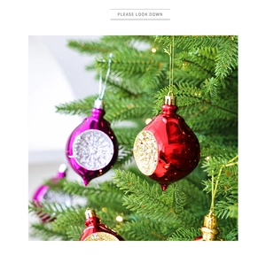 Detail van kleurrijke kersthangers in druppelvorm met glitters aan een kerstboom