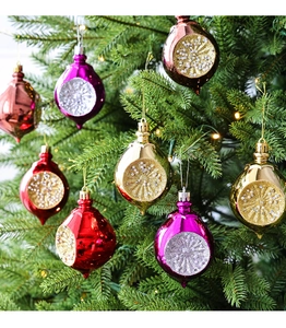 Detailopname van druppelvormige kersthangers met glitters op een verlichte kerstboom