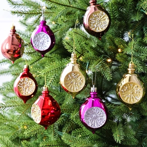 Hangende kerstballen in druppelvorm met glitters en parels aan groene boomtakken