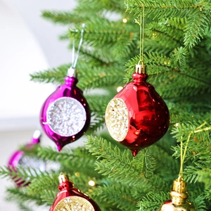 Kerstversiering in druppelvorm in rood en paars met glitter op de kerstboom