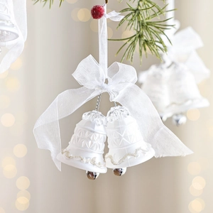 Weiße Weihnachtsglocken mit silbernem Glitzer und Schleife hängen am Tannenbaum