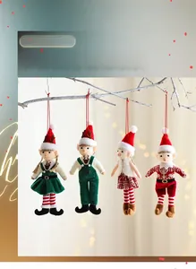 Detail of four festive Christmas elf dolls hanging on white branches with bokeh lights