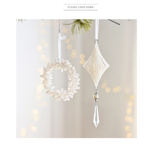 Close-up of white glittery Christmas wreath and geometric pendants with silver beads