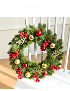Close-up of artificial pine Christmas wreath with red berries and golden baubles on a chair