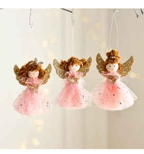 Three plush pink angel ornaments with gold wings hanging in warm festive lighting