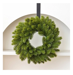 Close-up of thick green PE artificial Christmas wreath with dense needles on a black hook