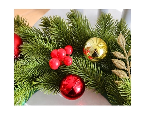 Macro detail of Christmas wreath with green needles, red berries, and gold festive ornaments