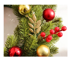 Close-up of artificial green Christmas wreath with red berries and golden ball ornaments