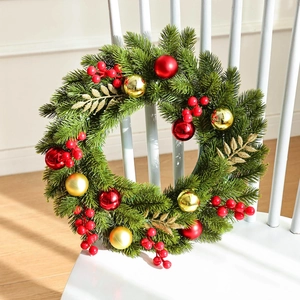 Classic Christmas wreath with red berries and gold ornaments on a white wooden chair