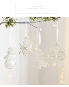 Close-up of glittery white Christmas ornaments including snowmen and bells on a tree