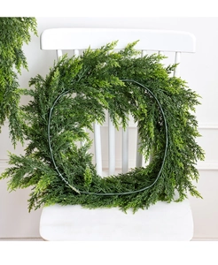 Ghirlanda di cedro verde artificiale su sedia bianca per decorazioni da parete
