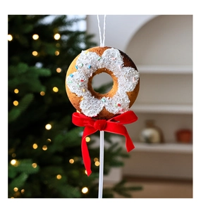 Détail d'un ornement de beignet avec glaçage et nœud en velours rouge pour sapin de Noël
