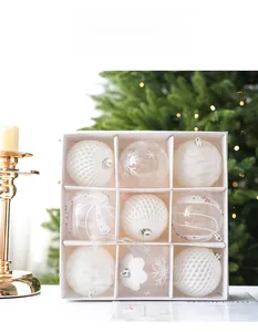 Detailed view of nine assorted white Christmas ornaments in a gift box with tree background