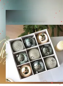 Detail of nine festive Christmas ornaments in forest green and champagne gold in a box