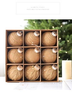 Detail of nine champagne gold glitter Christmas baubles in a rustic kraft paper gift box