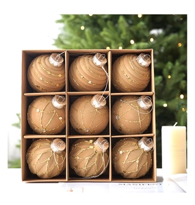 Detailed view of nine flocked Christmas balls with gold glitter patterns in a gift box