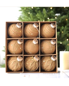 Close-up of 9 champagne brown Christmas ornaments with gold glitter in a kraft gift box